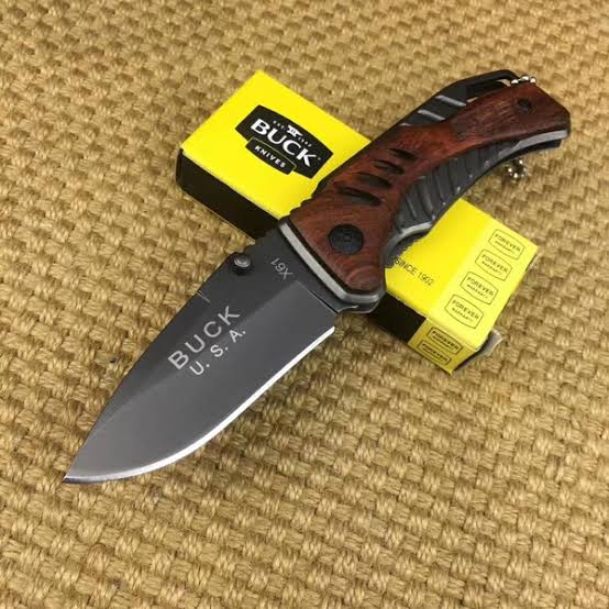 Folding knife with wooden handle and 'Buck' branding on a textured surface