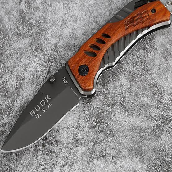 Folding knife with wooden handle on a gray textured surface
